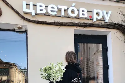 Покупательница с букетом у цветочного магазина Цветов.ру